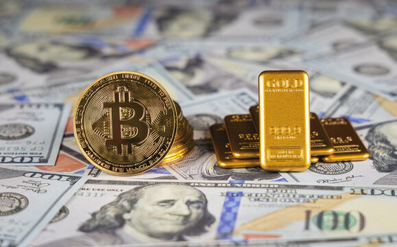 Des lingots d'or et des pi&egrave;ces de bitcoin pos&eacute;s sur des billets de banque en dollars. Concept de dollar vs or et bitcoin.