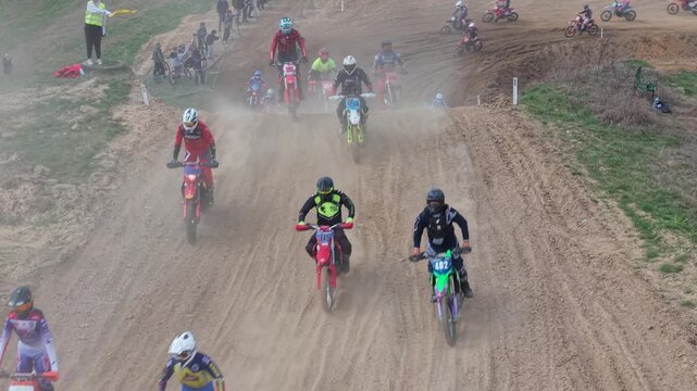 Aerial drone footage of motocross cross country race, dirt bikes speeding on rugged track, riders competing in off-road extreme motorsport event, dynamic action and dust clouds