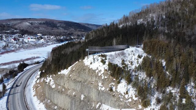Aerial shot of the twisted wooden tunnel observation deck in Matapedia, Quebec. Spectacular drone view of the cliffside lookout at the junction of the Matapedia and Restigouche rivers in autumn.