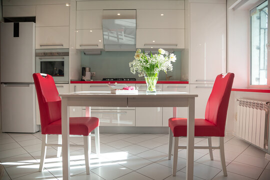 Pink baked nuts with filling and rosebuds in a white box with a card with two hares and hearts on a white table with a vase of wildflowers in the kitchen