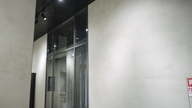 Empty lit corridor with fire alarm and ventilation grid on grey walls. Interior of modern business center representing minimalist style