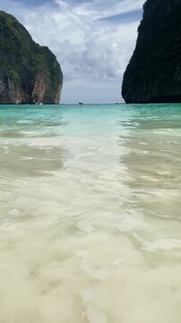 Maya Bay white sand beach and azure water vertical video, paradise tropical island scenery in Thailand.
