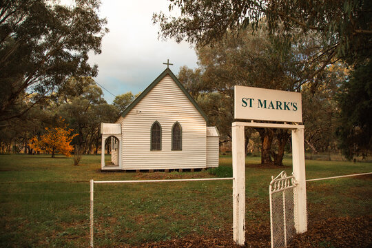Small white country church with St Mark's sign and gate in rural landscape