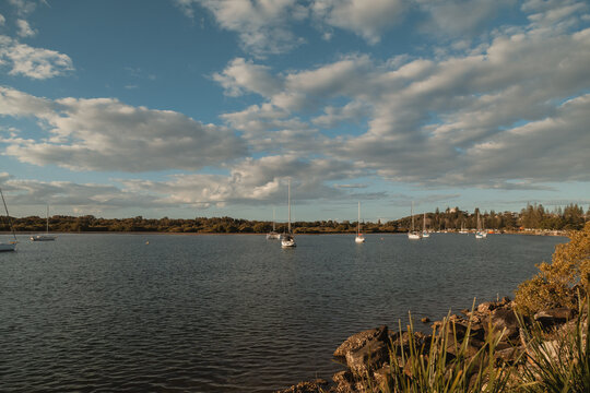 Sailboats anchored in a calm bay under a cloudy sky at Yamba NSW