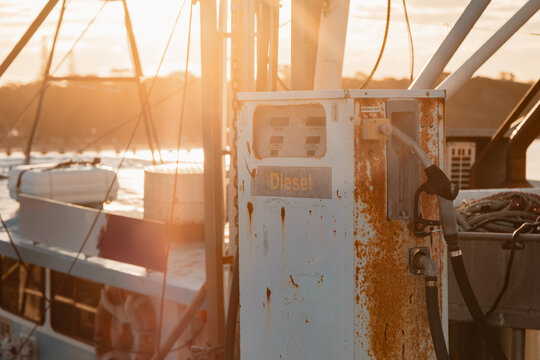 Old rusty diesel fuel pump on a boat jetty at sunset with warm golden hour light