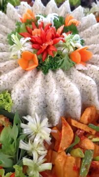 A vibrant and detailed view of Indonesian Tumpeng Nasi Daun Jeruk (Lime Leaf Rice) surrounded by traditional side dishes, decorated with beautiful vegetable carvings and garnishes