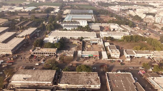 Featuring rows of small retail shops along the main road and large factory units in the background.