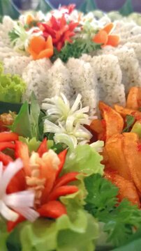 A vibrant and detailed view of Indonesian Tumpeng Nasi Daun Jeruk (Lime Leaf Rice) surrounded by traditional side dishes, decorated with beautiful vegetable carvings and garnishes