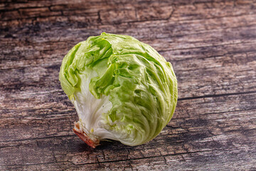 Fresh head of iceberg lettuce on a rustic dark wooden table background. © Andrei Starostin
