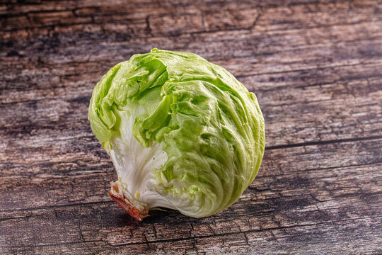 Fresh head of iceberg lettuce on a rustic dark wooden table background.