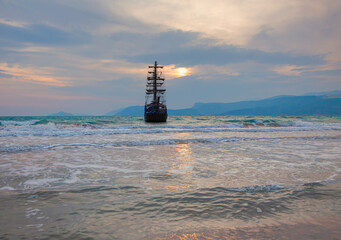 Sailing old ship in storm sea heavy sunset clouds in the background