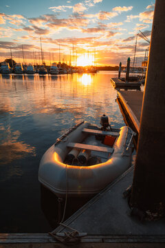 Golden sunset over a marina with a small inflatable boat docked by the pier