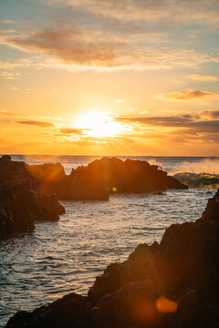 Waves crashing against rocks at sunrise
