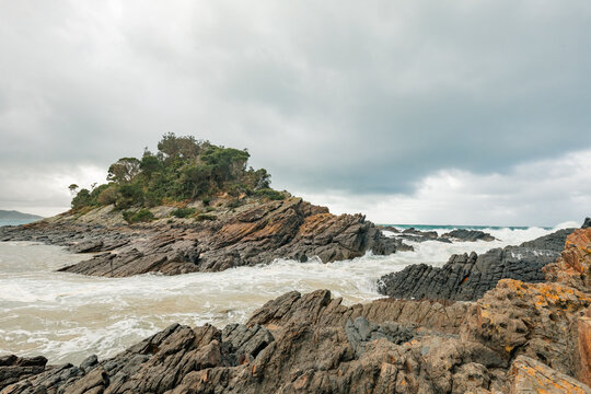 Rugged coastline with dramatic rock formations and crashing waves under a cloudy sky