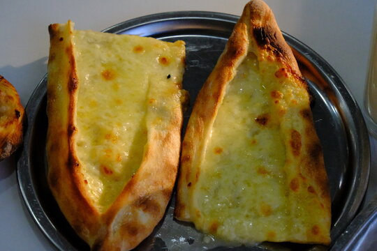 Close-up view of a pide Turkish flatbread with Kashar cheese. A glass of ayran yogurt drink. Ramadan pide. Iftar meal. Traditional Turkish cuisine. Hot, freshly baked pide. Healthy eating.