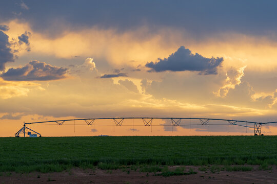 A dramatic sunset sky behind a large farm irrigation sprinkler