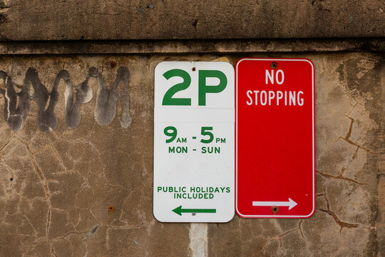 2p hour parking sign on concrete wall at beach with no stopping red sign