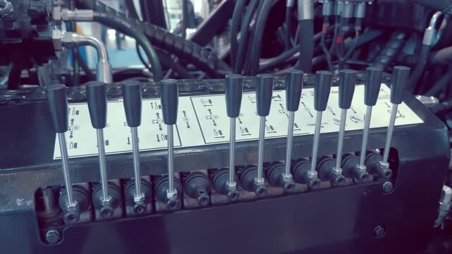 Rows of levers on hydraulic, pneumatic control block on industrial equipment. Closeup. Shot in motion