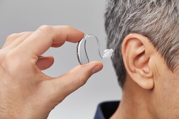 Fototapeta premium Hand Holding a Hearing Aid Ready to Be Inserted in Ear