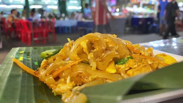 Thai Pad Thai noodle dish close-up at a street food stall, authentic Thai cuisine with egg and bean sprouts.