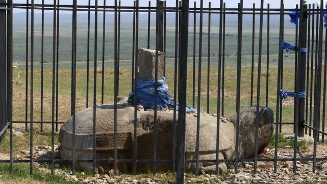 The big rock figure of the turtle behind the iron fence is the Karakorum turtle. On a Sunny summer day. Kharkhorin, Mongolia.