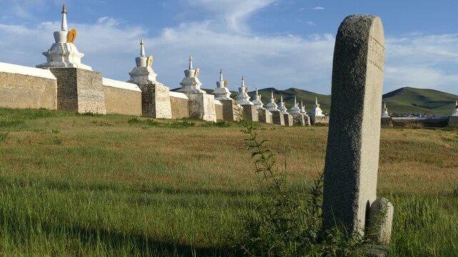 Stone stele on the background of the walls of the ancient Buddhist monastery Erdene Zuu, Kharkhorin, Mongolia. Stupas are sacred Buddhist structures, masonry. Sunny summer evening.
