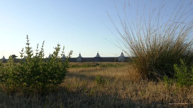 Rocky wall and stupas of the old Buddhist monastery of Erdene Zuu against the blue sky. Kharkhorin, Mongolia. The stupa is a sacred Buddhist structures. Sunny summer evening.