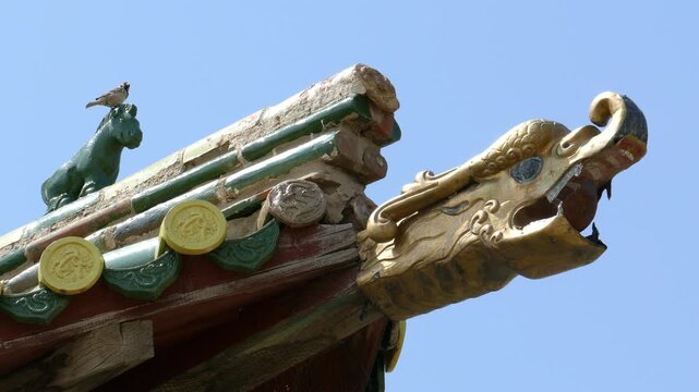 Bird sits on the roof of an ancient Buddhist pagoda, decorated with figures of mythical animals. One of the temples of  Erdene Zuu monastery, Kharkhorin, Mongolia.
