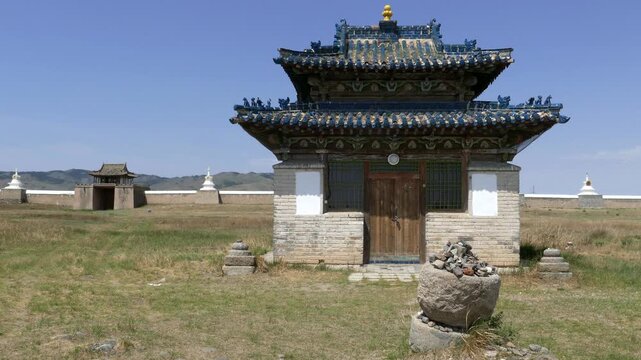 Temple in the form of a pagoda, gate and rocky wall with stupas of the ancient Buddhist monastery of Erdene Zuu against the blue sky. Kharkhorin, Mongolia. The stupa is a sacred Buddhist structure.  