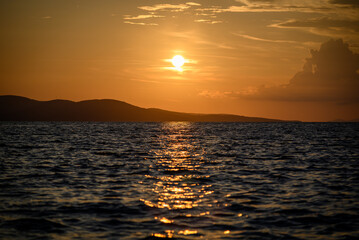 Obraz premium Golden sunset over ocean with island silhouettes