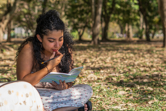 Woman writing in park journaling thoughts and ideas