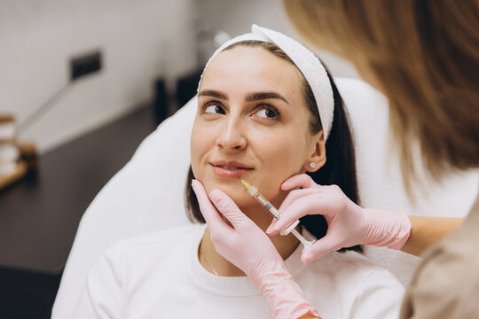 Woman getting dermal fillers injected into lips by a cosmetologist, focusing on beauty and facial enhancements