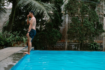 Naklejka premium Man diving into pool surrounded by greenery
