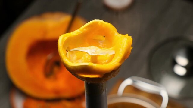 Close up of working part of immersion blender with blades after mixing yellow fruit pieces. Hot steam coming from blender blades. Cooking puree soup or porridge using immersion blender.