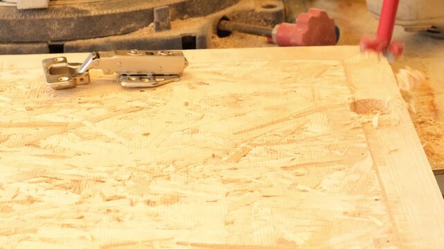 Drilling hinge recess in cabinet door using special cutter. Installing door hinges on new wooden furniture. Furniture production from wood in private workshop. Small business, artisan workshop.