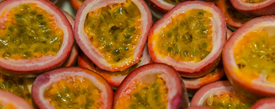 Passion fruit background with half cut chinola. A lot of sliced maracuja. Tropical fruits backdrop.