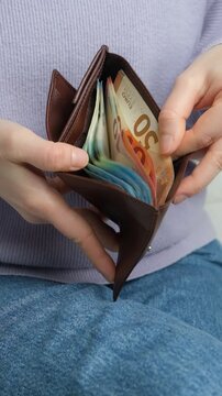 Wallet with euro banknotes in hands, vertical slow motion.