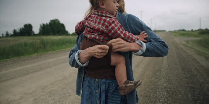 Young mother on country road putting her baby in a sling