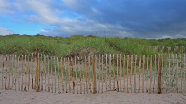 Sandige D&uuml;nen mit einem Holzzaun vor einem bew&ouml;lkten Himmel, Seahouses, Northumberland, England, Gro&szlig;britannien