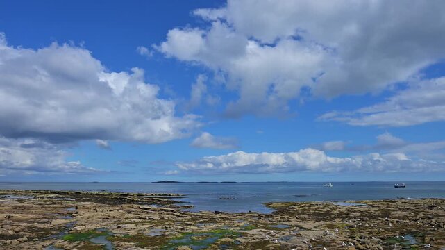 Felslandschaft unter blauem Himmel und Wolken mit Blick aufs Meer, Seahouses, Northumberland, England, Gro&szlig;britannien