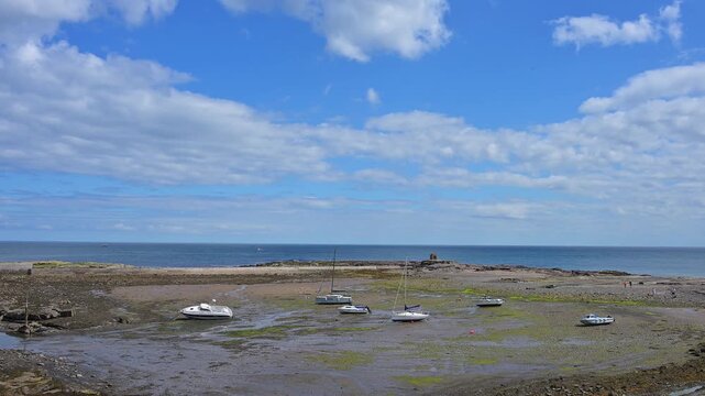 Boote liegen auf trockenem Boden bei Ebbe vor einem felsigen K&uuml;stenabschnitt, Seahouses, Northumberland, England, Gro&szlig;britannien