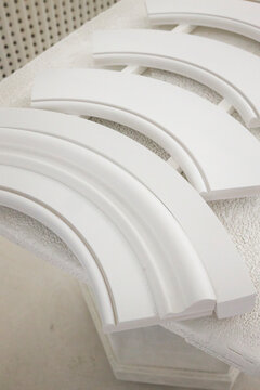 Detail of a custom curved millwork in white spray booth with worker hands