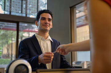 Guest takes room key card during check-in process at the hotel counter. Business travelling guest receiving room access.