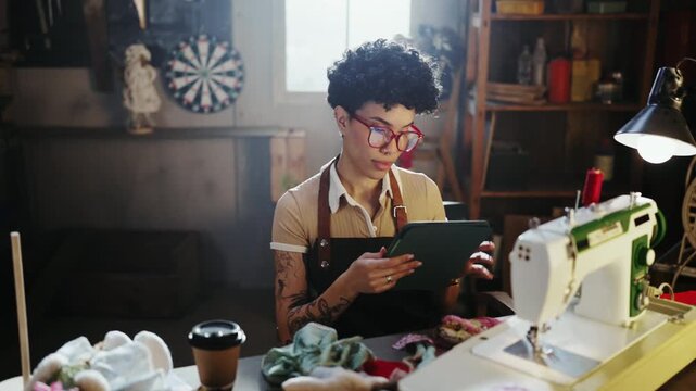 Creative entrepreneur using tablet in workshop surrounded by handmade products. Concept of ecommerce, digital business and modern craftsmanship.
