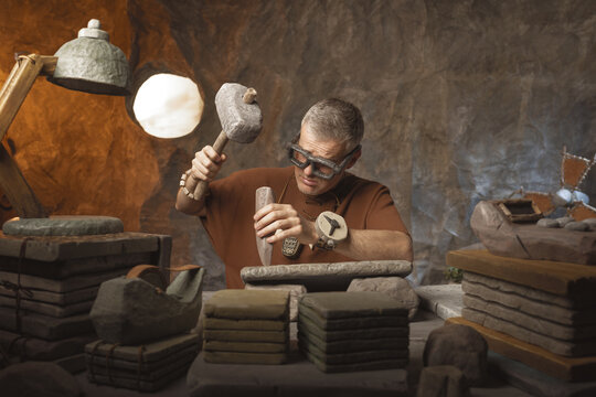 Hard-Working Prehistoric Clerk: Funny Caveman Carving Stone Tablets with Hammer and Chisel in Cave Office