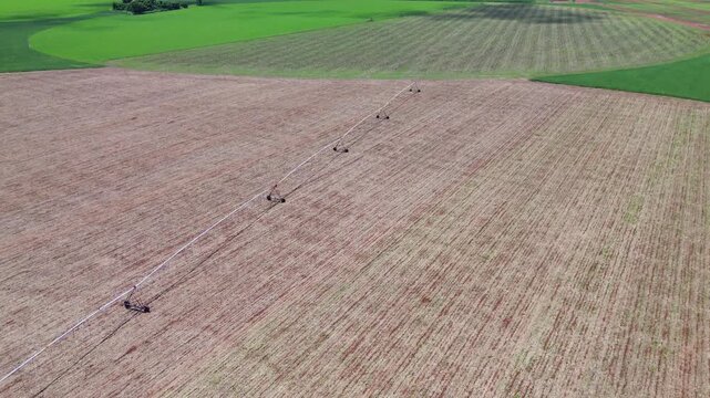 Aerial drone view of center pivot irrigation system in Brazilian rural field with dark storm clouds and rain in the background. Agriculture water management and weather concept.
