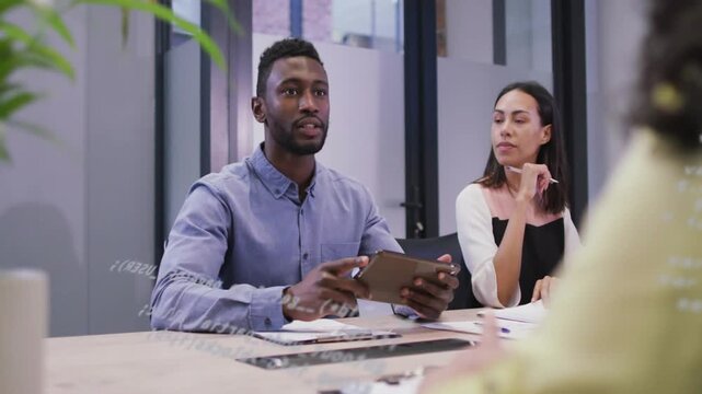 Man tapping tablet and speaking, woman listening, guest reaching to shake hands, sealing deal