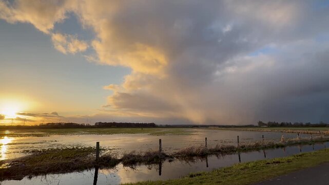 Wetterwolke im Sonnenuntergang im Naturpark D&uuml;mmer Deutschland, Dramatische Wolken im warmen Abendlicht &uuml;ber &uuml;berfluteter Wiese mit Spiegelung
