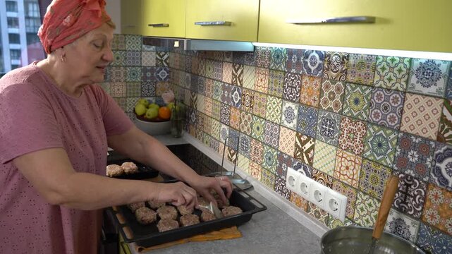 Senior woman bake fry meatballs on a baking sheet. Cooking food at home