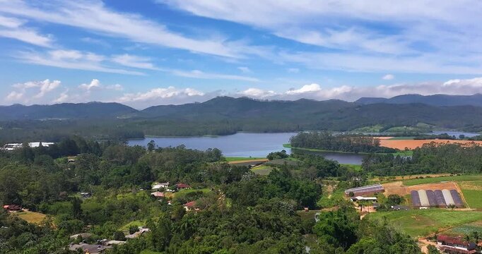 4K aerial drone view of Alto Tiete reservoir in Brazil, showing water storage, rural landscape, forests and agricultural fields under blue sky.